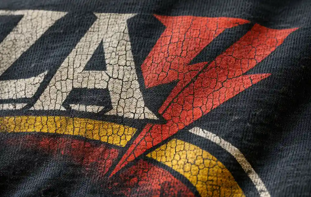 Detailed view of natural cracked screen print on a faded vintage band tee.