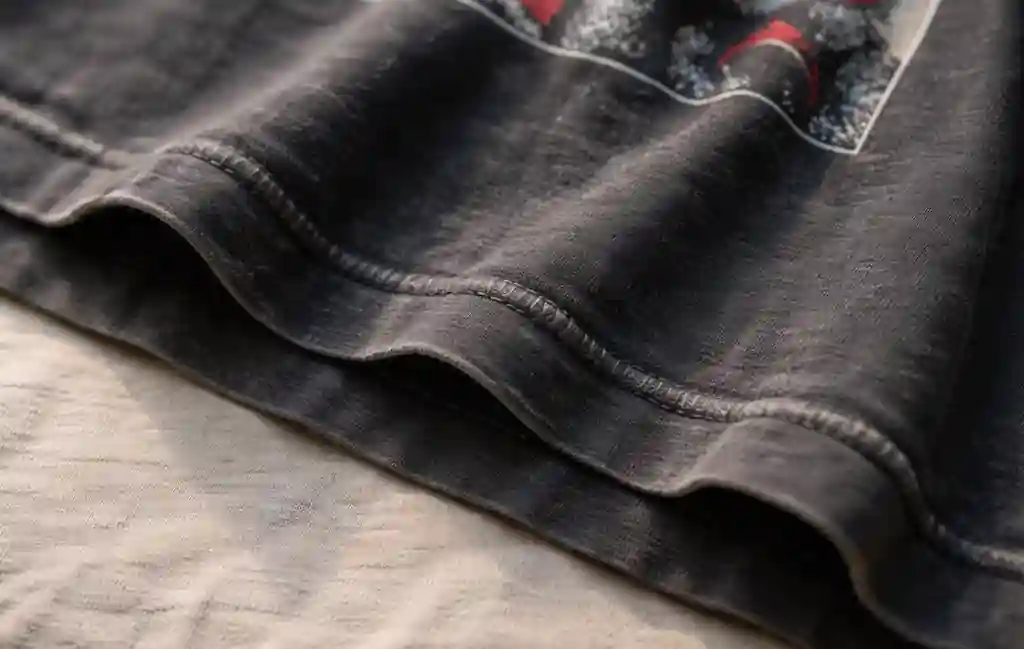 Close-up detail of a vintage band tee showing single stitch hem and aged cotton texture.