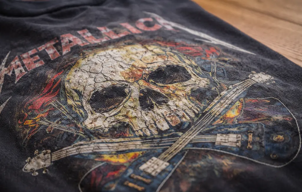 Close-up of a cracked vintage band tee graphic showing aged screen print texture